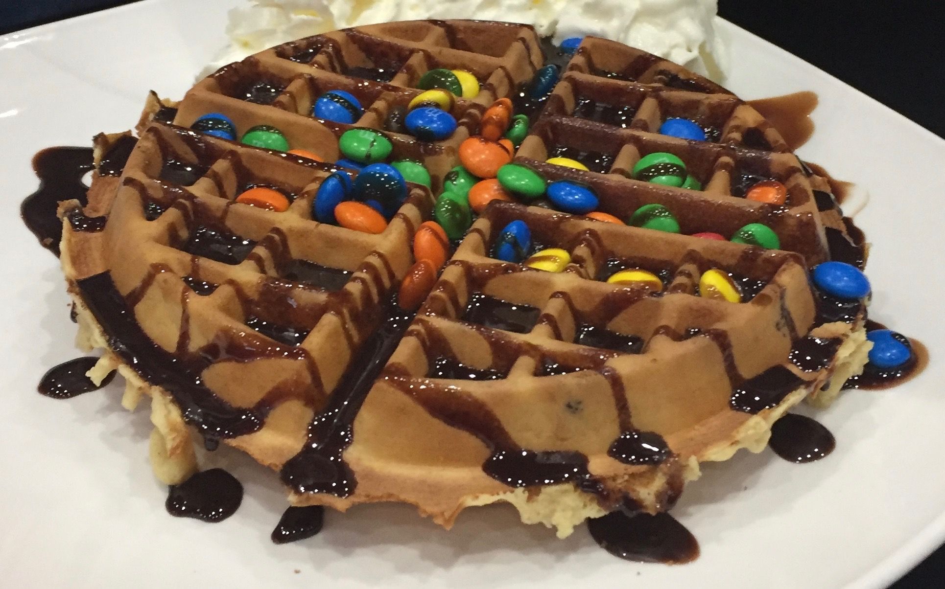 A waffle topped with chocolate sauce and beanies.